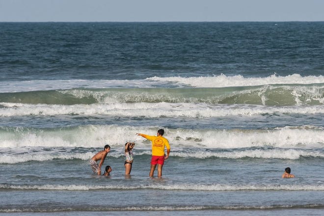 A lifeguard talks to kids in the water in New Smyrna Beach recently when Volusia County Beach Safety Ocean Rescue was flying a high hazard warning flag. [Lola Gomez/News-Journal]