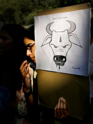 In this Oct. 2, 2015 file photo, a student activist holds a placard during a protest denouncing the killing of a 52-year-old Muslim farmer Mohammad Akhlaq by villagers upon hearing rumors that the family was eating beef in New Delhi, India. A human rights group on Friday expressed concern over rising brutal attacks in India by self-appointed "cow protectors" against Muslims and lower castes over rumors that they sold, bought or killed cows for beef. (AP Photo/Altaf Qadri, File)