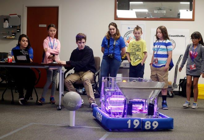 Photo by Daniel Freel/New Jersey Herald - Vernon Township High School robotics team member Brian Hill, third from left, helps young children learn how to drive the team’s robot on Thursday at Selective in Branchville. The children were spending the day with their parents as part of “Take Our Daughters and Sons to Work Day.”