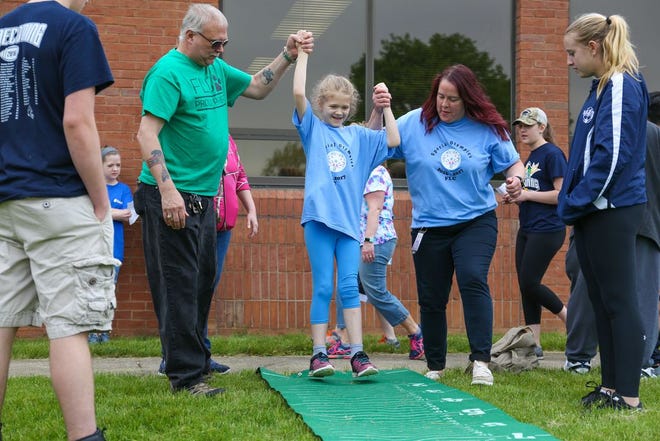 Vanessa Neidig, center, with the help of her grandfather, James Neidig and personal care assistant Donna Tillis, performs the long jump at Special Olympics Field Day at Franklin Learning Center.