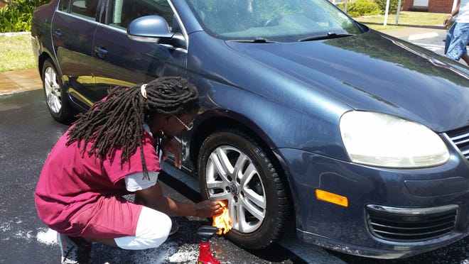 James Bush, a childhood friend of Brandon Mackey who was shot to death earlier this month, washes vehicles Saturday at Frontier Church in Leesburg as part of a fundraiser for the victim’s family. [MILLARD K. IVES / DAILY COMMERCIAL]