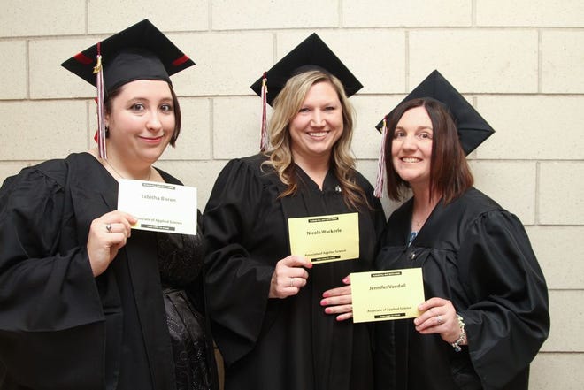 Three friends, Tabitha Boron, Nicole Wackerle and Jennifer Vandall flash their name cards as they await their turn to enter the gymnasium for their graduation commencement from MCCC on Friday night.