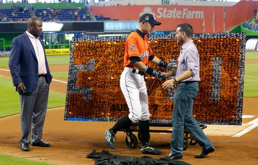 Miami Marlins' Ichiro Suzuki, center, shakes hands with club president David Samson, right, as Michael Hill, president of baseball operations, looks on during a pregame ceremony honoring Ichiro's 3,000th career hit before a baseball game against the Pittsburgh Pirates, Sunday, April 30, 2017, in Miami. (AP Photo/Lynne Sladky)