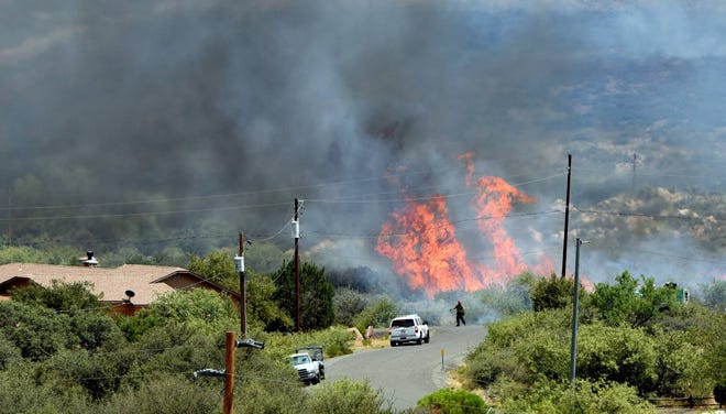 In this June 28, 2016, file photo, brush burns near a home on the Bug Creek Fire near Cordes Lakes, Ariz. Forecasters are predicting significant wildfire activity this summer across the Southwest, Florida, Georgia, as well as in portions of California and Nevada. (Les Stukenberg/The Daily Courier via AP, file)
