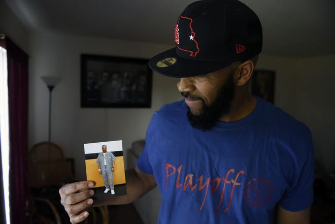 Dont'e Epps stands in his house April 18 holding a photo of his brother, Paige Spears, who has been in prison for 29 years for a robbery in Ferguson, Mo. Epps and his sister, Jacqueline Spears-Williams, have been working to get Paige out of prison for the last six years. [Sarah Bell/Tribune]