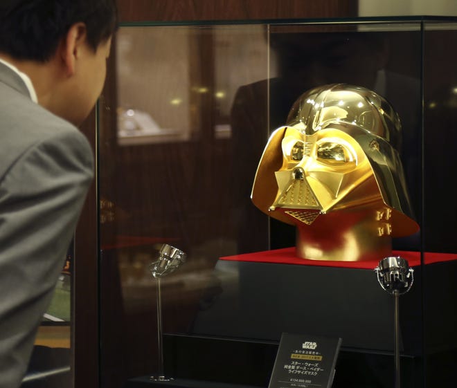An employee of Tokyo gold jeweler Ginza Tanaka looks at the gold mask of Darth Vader at the jewelry shop in Tokyo, Monday, May 1, 2017. The life-size mask of Star Wars villain Darth Vader will be up for sale for a hefty price of 154 million yen ($1.38 million). The 24-karat mask was created by the gold jeweler to mark the 40th anniversary since the release of the first Star Wars film. THE ASSOCIATED PRESS