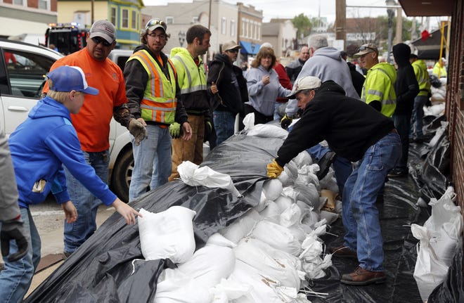 Volunteers place sandbags to protect buildings from potential floodwater Monday in Eureka. Torrential rain caused Missouri waterways to burst their banks over the weekend forcing hundreds of road closures and causing people to take precautions against possible flooding. [Jeff Roberson/AP]