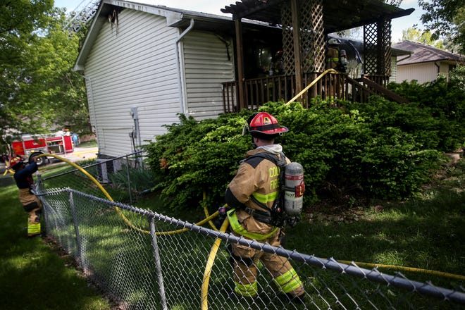 A Columbia firefighter pulls a hose while responding to a house fire Friday in the 3900 block of Cannon Court in northeast Columbia. Firefighters arrived around 3:20 p.m. and saw flames coming from the back of the home, Division Chief Clayton Farr Jr. said. It took firefighters 15 minutes to bring the fire under control, and no one was injured, he said. Farr did not know if anyone was in the home at the time of the fire. [Timothy Tai/Tribune]