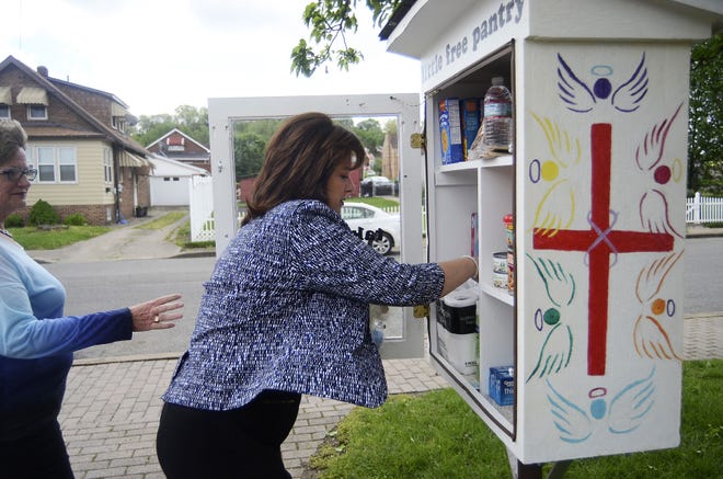 Megan Grabski, left, reaches to help Denise Drabeck stock nonperishable food and household products in the Little Free Pantry at House of Prayer Lutheran Church in Aliquippa.