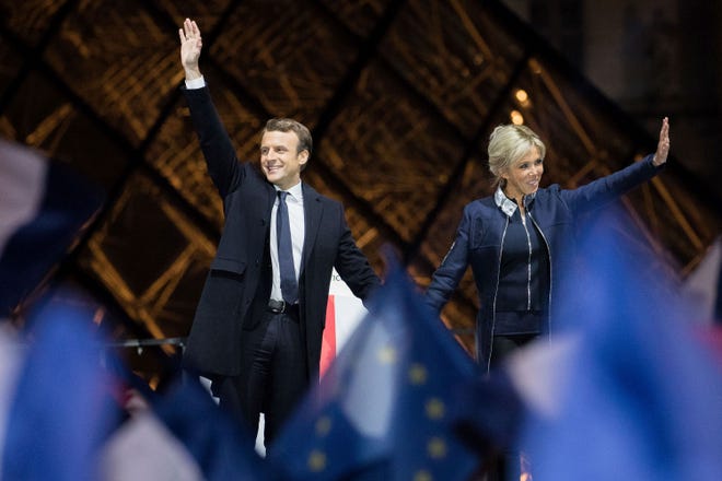 Emmanuel Macron, France's next president, and his wife, Brigitte Trogneux, wave after Macron delivered a speech at the Louvre Museum in Paris on Sunday. Macron pledged to unite France's rifts after his victory over Marine Le Pen in the presidential election, saying that he'll work to address the concerns that were exposed during one of the most divisive campaigns of recent history. CHRISTOPHE MORIN/BLOOMBERG
