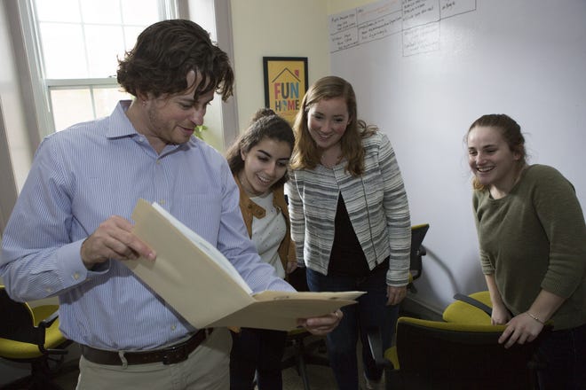 Holy Cross professor K.J. Rawson shows an old document to students Mithra Salmassi, Isabel Tehan and Galen Comerford. The team is working on a transgender digital archive. [Photo/Matt Wright]