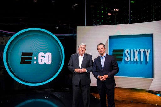 In this May 3, 2017 image released by ESPN, co-hosts Bob Ley, left, and Jeremy Schaap appear on the set of the revamped Sunday magazine series, “E:60,” in Bristol, Conn. The first new “E:60,” featuring a story about the Syrian national soccer team, airs Sunday at 9 a.m. ET. (Joe Faraoni/ESPN via AP)