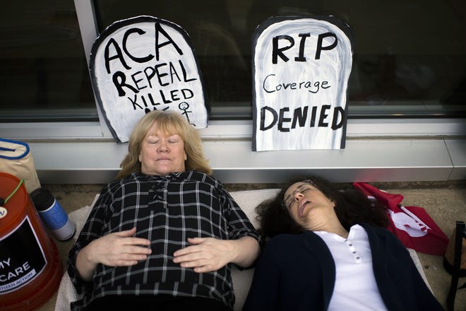 Maureen Quinn, left, and Maria Palmer pretend to be dead as protestors gather before a town hall held by New Jersey Republican Rep. Tom MacArthur in Willingboro, N.J., Wednesday, May 10, 2017. MacArthur, a Republican who played a key role in helping the GOP-led U.S. House pass an Affordable Care Act replacement bill planned to meet with voters on Wednesday in his first town hall since the bill passed. THE ASSOCIATED PRESS