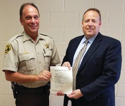Sheriff Rick VanBrooker, left, presents Detective Billie McDonoald with a letter of appreciation for his work in solving a recent burglary.