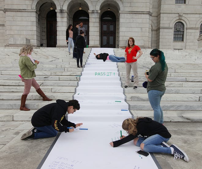 People sign petition draped over the State House steps on Saturday. The petition was in support of a reproductive-rights bill in the General Assembly. At bottom are Jillian Aronhalt, left, 16, of East Providence, and her friend Megan Arno, 15, of Pawtucket. [The Providence Journal/Glenn Osmundson]