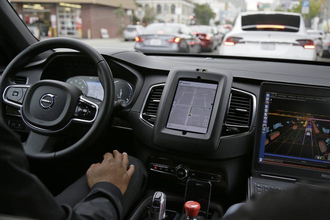 FILE - In this Tuesday, Dec. 13, 2016, file photo, an Uber driverless car waits in traffic during a test drive in San Francisco. In just a few years, well-mannered self-driving robotaxis will share the roads with reckless, law-breaking human drivers. The prospect is causing migraines for the people developing the robocars and is slowing their development. But experts say eventually the cars will coexist with human drivers on real roads. (AP Photo/Eric Risberg, File)