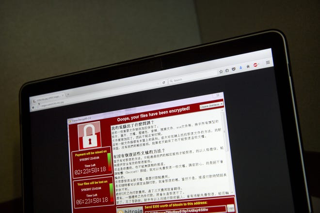 FILE - In this May 13, 2017 file photo, a screenshot of the warning screen from a purported ransomware attack, as captured by a computer user in Taiwan, is seen on laptop in Beijing. Global cyber chaos is spreading Monday, May 14, as companies boot up computers at work following the weekend's worldwide "ransomware" cyberattack. The extortion scheme has created chaos in 150 countries and could wreak even greater havoc as more malicious variations appear. The initial attack, known as "WannaCry," paralyzed computers running Britain's hospital network, Germany's national railway and scores of other companies and government agencies around the world. (AP Photo/Mark Schiefelbein, File)