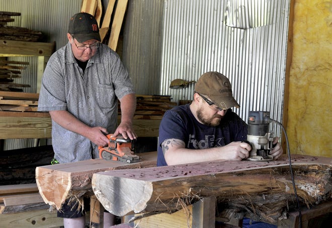 Darren Pemberton, left, and his son Richard work on a split red cedar log at their workshop at Possum Hollow Handcrafted Woodworks.