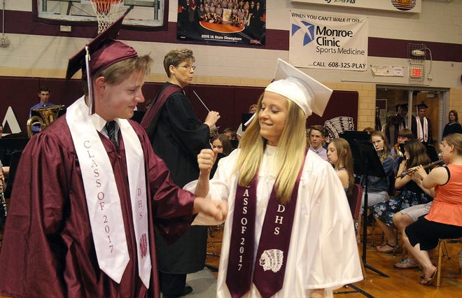 Elaine Zimmerman (right) gives a fist bump to Jace Bardell during the processional for commencement exercises on Tuesday, May 16, 2017, at Dakota High School. [JANE LETHLEAN/THE JOURNAL-STANDARD CORRESPONDENT]