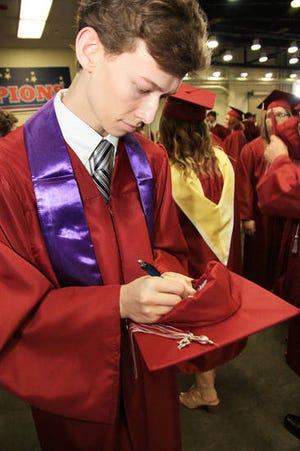 Edmond Memorial High School senior Dustin Galley writes his name inside his mortar board before his graduation ceremony. [PHOTO BY THOMAS MAUPIN, FOR THE OKLAHOMAN]