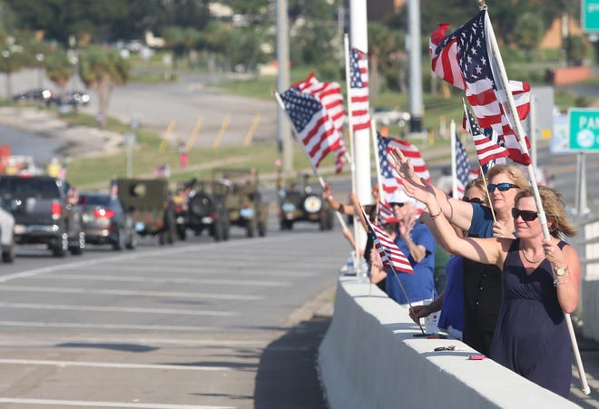 Beth Arnold, right, waves a flag with other supporters of veterans during the Warrior Beach Retreat parade in September 2016. People are encouraged to line the Hathaway Bridge again Thursday afternoon. [PATTI BLAKE/NEWS HERALD FILE PHOTO]