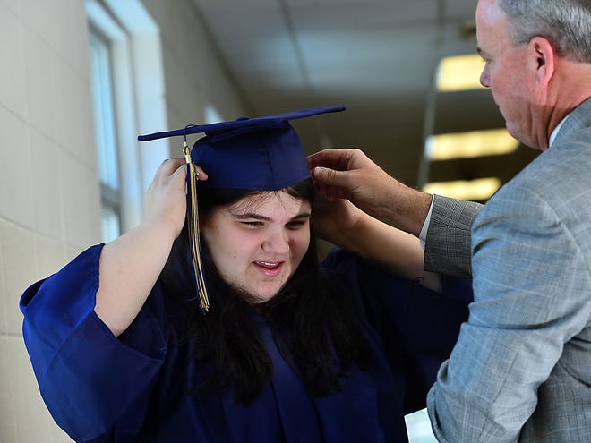 Heather Dunnaway, 17, gets help trying on her graduation cap from Jeff Stevens, Spartanburg High principal. Stevens spent time getting to know Dunnaway after learning she had lived most of her life in motels. [ALEX HICKS JR./SPARTANBURG HERALD-JOURNAL]