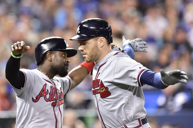 Atlanta first baseman Freddie Freeman, right, celebrates after hitting a two-run home run with second baseman Brandon Phillips during fifth inning interleague baseball action against in Toronto on Tuesday. [FRANK GUNN/THE CANADIAN PRESS]