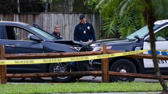 Police examine an SUV that rammed a police car at Palmetto Park at Nathan Hale Road before dawn Monday, May 15, 2017. (Lannis Waters/The Palm Beach Post)