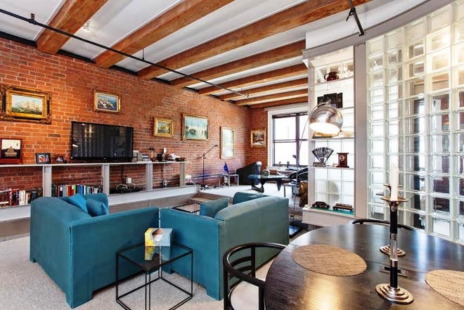In the open living room area, industrial steel beams are used in an open credenza-like display piece with another slightly curved and tapered top juxtaposed against the original exposed brick wall.