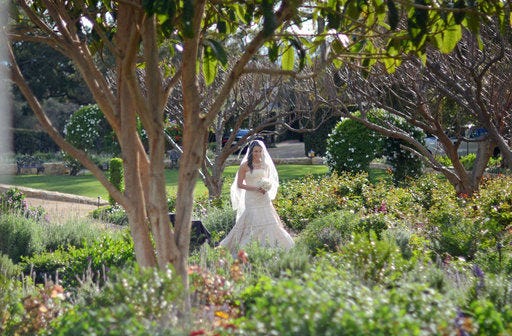 In this Feb. 28, 2015 photo, Samantha Becker makes her way through a garden while walking to her wedding ceremony on the grounds of San Ysidro Ranch in Santa Barbara, Calif. From the liquor to the linens, choosing a wedding venue requires attention to details. (AP Photo/Benny Snyder)