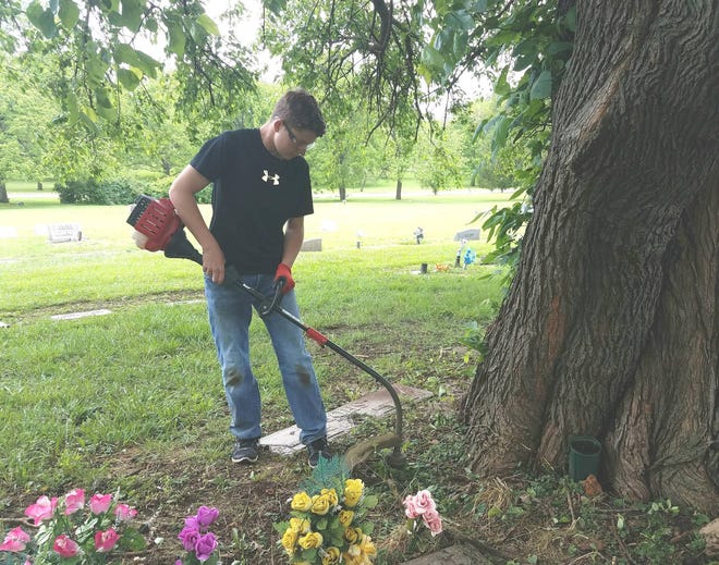 Tyler Moser, 14, who will be a freshman at Seaman High School in the fall, cleans around a flower bed at the Topeka Cemetary on Saturday during Keep America Beautiful’s clean up day before Memorial Day on May 29. (Angela Deines/The Capital-Journal)