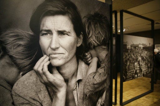 In this photo taken Thursday, May 11, 2017, the iconic photograph Migrant Mother looks out at the exhibit "Dorothea Lange: Politics of Seeing," at the Oakland Museum of California in Oakland, Calif. The three major themes of the Lange display are the Great Depression, the home front during World War II and the urban decline and postwar sprawl in California. Running through August 13, the exhibit includes 100 of Lange's photographs, including recognized works as well as new, improved unframed prints that have been digitally scanned. (AP Photo/Eric Risberg)