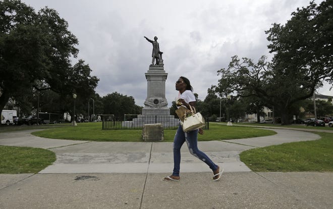 In this Sept. 2, 2015 file photo, a woman walks past a monument of Jefferson Davis on Jefferson Davis Parkway at Canal Street in New Orleans. The statue of Davis was removed by the city in May. [AP file]