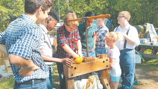 Greencastle-Antrim first-grader Adelynn Ebersole turns the crank on a cider press to make apple cider, with the help of eighth-graders Diego Gonzalez, Foday Bangura, Colby Bowen and Isaiah Toney-Mayhugh during Friday's 44th annual Cumberland Life Festival at Tayamentasachta Center for Environmental Studies.