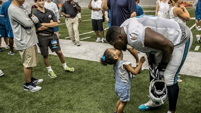 Miami Dolphins tackle Jermon Bushrod (74) gives his daughter a kiss after practice at Dolphins training camp in Davie, Florida on August 6, 2016. (Allen Eyestone / The Palm Beach Post)