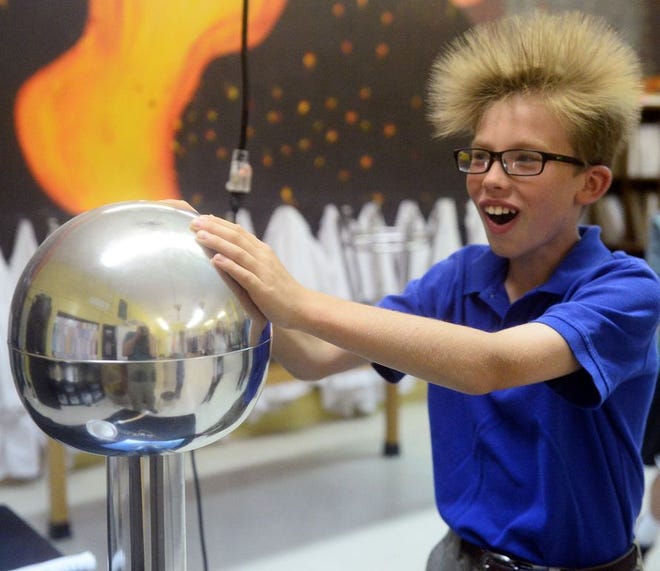 Timothy Hackman, a 6th-grade student at Blessed Sacrament School receives an electrostatic charge from a Van de Graaff generator to make her hair stand up during Family STEM Night.