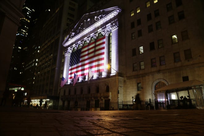 In this Friday, Feb. 17, 2017, file photo, an American flag hangs on the front of the New York Stock Exchange on an evening, in New York. Global stock markets traded in narrow ranges Wednesday, May 24, 2017, with investors brushing aside Moody's decision to cut China's debt rating. THE ASSOCIATED PRESS