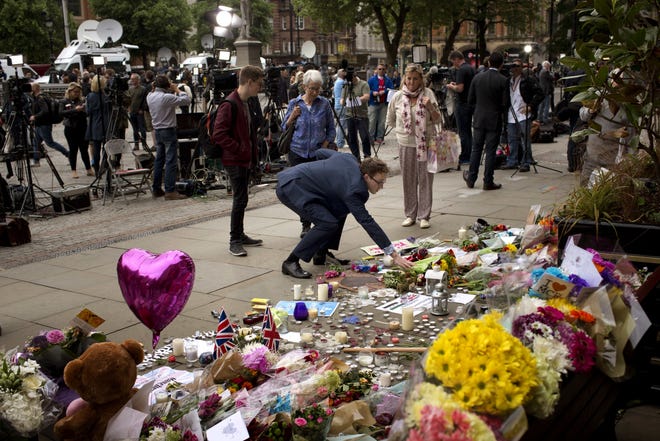 A man places flowers in Albert Square in Manchester, Britain, Wednesday, May 24, 2017, after the suicide attack at an Ariana Grande concert that left more than 20 people dead and many more injured, as it ended on Monday night at the Manchester Arena. THE ASSOCIATED PRESS