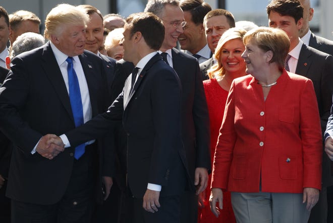German Chancellor Angela Merkel watches as President Donald Trump shakes hands with French President Emmanuel Macron during a ceremony to unveil artifacts from the World Trade Center and Berlin Wall for the new NATO headquarters, Thursday, May 25, 2017, in Brussels. THE ASSOCIATED PRESS