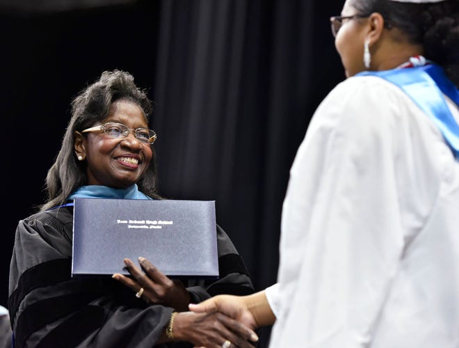 Duval interim school superintendent Patricia Willis (left) hands out diplomas during graduation ceremonies for Ribault High on Thursday at Veterans Memorial Arena in Jacksonville. (Will Dickey/Florida Times-Union)