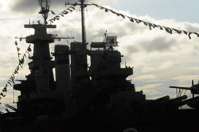 The setting sun silhouettes the Battleship North Carolina during the 51st annual Memorial Day observance in 2016. [STARNEWS FILE]