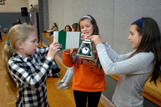 McKenzie Shaw, Lydia Ruksznis and Alexandra Nichols remove the battery pack from their car "Recycled Force" after racing in the annual fifth-grade solar car race at Marshwood Great Works School in South Berwick, Maine, on Friday. Cars raced indoors with battery packs instead of solar panels because of rain. [Ralph Morang photo]