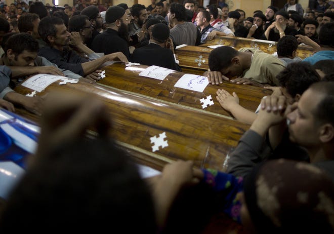 Relatives of Coptic Christians who were killed during a bus attack mourn by their coffins during a funeral service at Abu Garnous Cathedral in Minya, Egypt, on Friday. [AMR NABIL/THE ASSOCIATED PRESS]