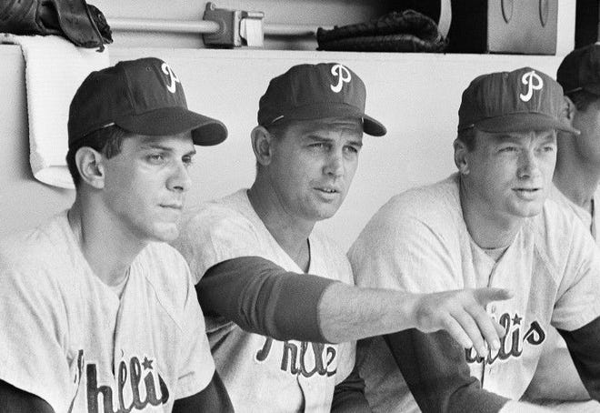 Philadelphia Phillies Manager Gene Mauch, center, and pitcher Jim Bunning, right, are shown in dugout at Shea Stadium as they studied New York batters, June 20, 1964, New York. On June 21, Bunning pitched a perfect game, retiring all 27 batters as the Phillies won 6-0 of the Mets in the first game of a double header. The man on the left is unidentified. (AP Photo)