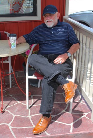 Hillsdale Academy golf coach, Charles Blood, enjoys a coffee outside Checker Records. [ANDREW KING PHOTO]