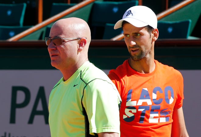 Defending champion Serbia's Novak Djokovic watches Andre Agassi, left, of the U.S, during a training session for the French Open tennis tournament at the Roland Garros stadium, Friday, May 26, 2017 in Paris. Agassi is Djokovic's new coach. (AP Photo/Christophe Ena)