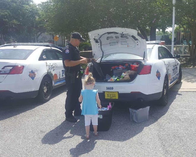 Officer Mark Wohlin with the Fort Walton Beach Police Department lets a child pick out toys from his police cruiser. [SPECIAL TO THE DAILY NEWS]