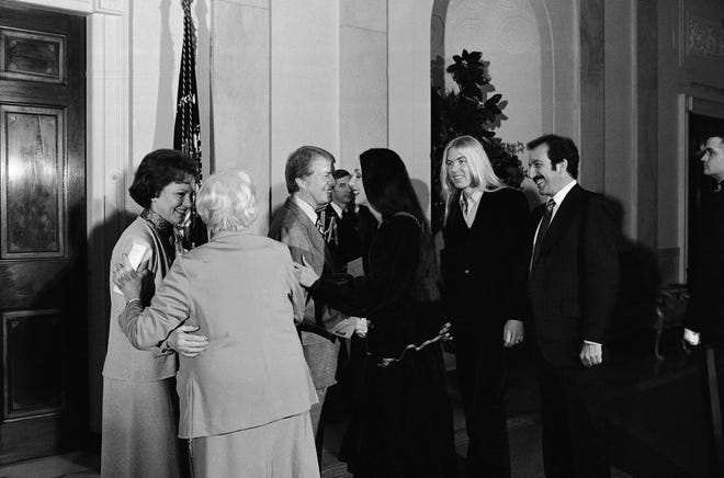 President Jimmy Carter greets singer Cher as her husband Gregg Allman stands second from right during a reception at the White House, Jan. 21, 1977 in Washington held by the Carters for the Georgia Peanut Brigade, a group of campaign workers. [AP Photo/Peter Bregg]