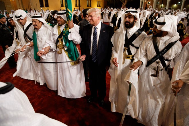 In this Saturday, May 20, 2017 file photo, President Donald Trump holds a sword and sways with traditional dancers during a welcome ceremony at Murabba Palace, in Riyadh, Saudi Arabia.
