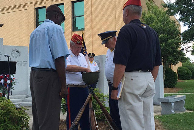 BURNING OF NAMES — Pictured left to right, Glenn Dixon, Bill Beeson, Terry Brown and Harvey Allred burn the names of veterans who died in the past year during the Randolph County Memorial Day service in Asheboro on Monday. (Annette Jordan/The Courier-Tribune)